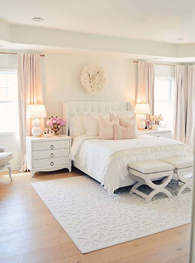 Dormitorio clásico cama grande con almohadas. Mesitas de noche con dos lámparas. Alfombra y paredes blancas