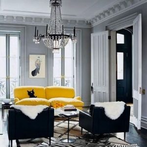 Un sofá de cuero amarillo ilumina la decoración de una sala de estar gris y complementa idealmente los sillones negros
