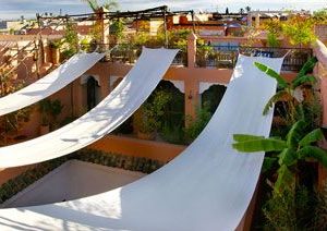 Brise-soleil realizado con tiras de lona blanca en una terraza de estilo mediterráneo
