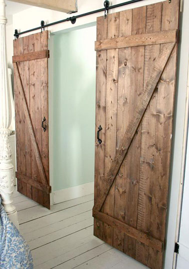 Para ahorrar espacio y como alternativa a una puerta clásica, esta puerta de madera corrediza doble montada sobre rieles, hecha por usted mismo, agrega encanto al dormitorio. 