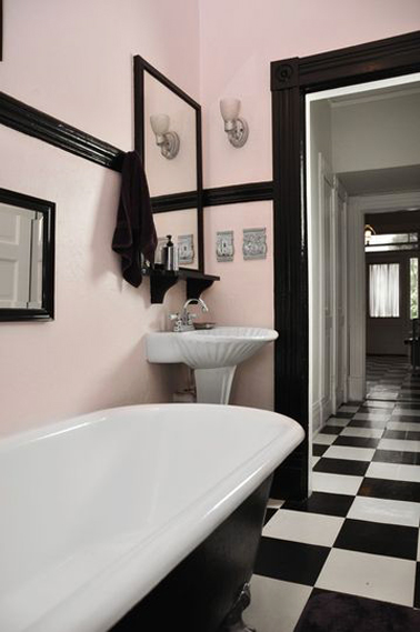 En un baño retro ya equipado con una bañera independiente, es la pintura rosa pálido en las paredes subrayada con una tira de pintura negra lo que completa el estilo.  Para mantener la armonía, espejo y ropa de baño negra.