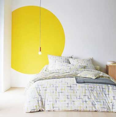 Una ronda de pintura amarilla impactante anima la decoración de esta elegante habitación blanca.  Dibujar una forma gráfica es una idea para despertar una habitación monocromática