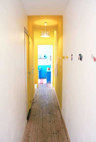 Parte del pasillo está pintado con un color amarillo para brindar alivio y luz a este espacio estrecho.  Para mayor efecto, una luminaria ilumina el amarillo. 
