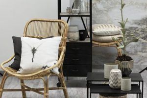 La decoración contemporánea de esta pequeña sala de estar que combina colores naturales y un elegante negro se complementa muy bien con un sillón de ratán natural y su taburete a juego.