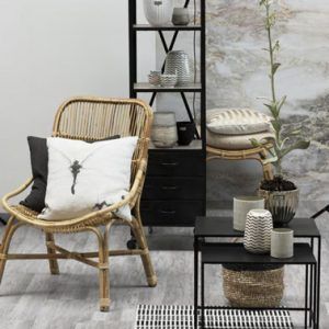 La decoración contemporánea de esta pequeña sala de estar que combina colores naturales y un elegante negro se complementa muy bien con un sillón de ratán natural y su taburete a juego.