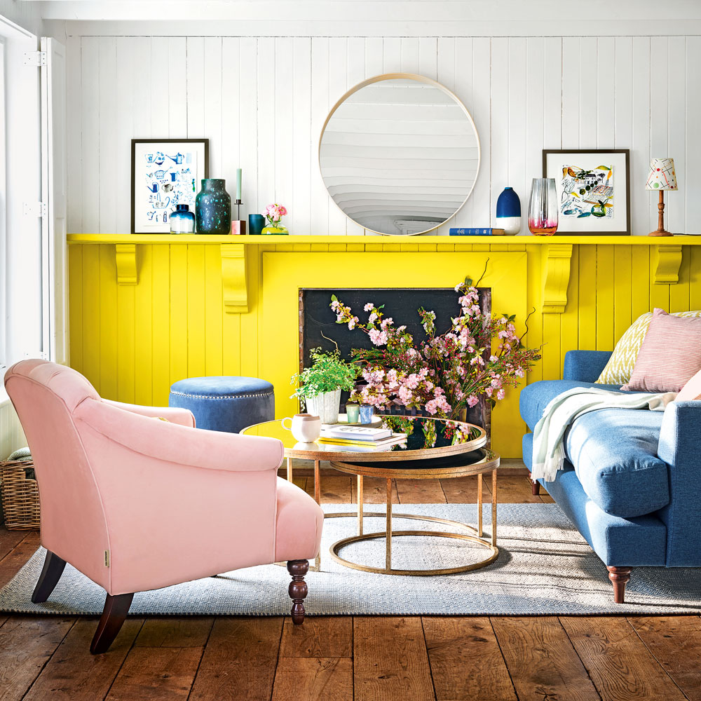 Una sala de estar gris pálido con una pared pintada de amarillo brillante y una chimenea