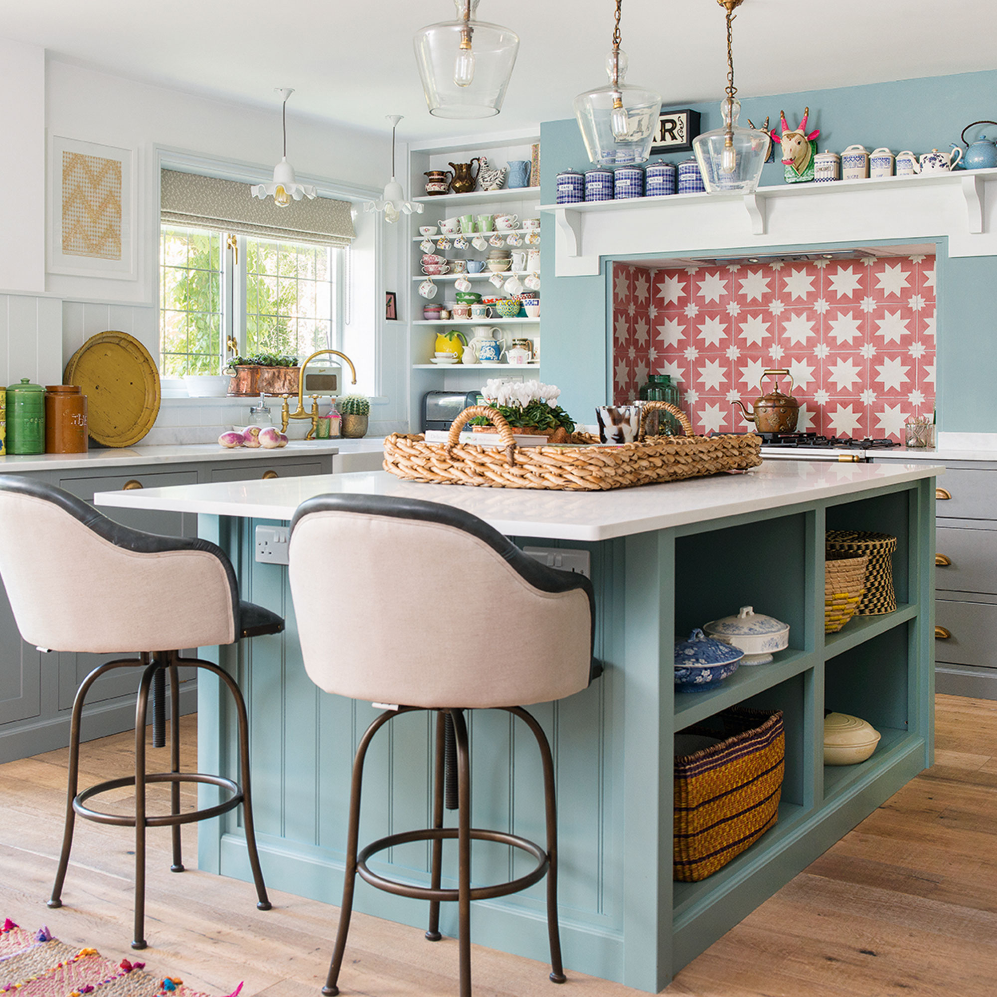 Cocina azul claro con isla, asientos de barra y salpicadero de azulejos estampados en rosa