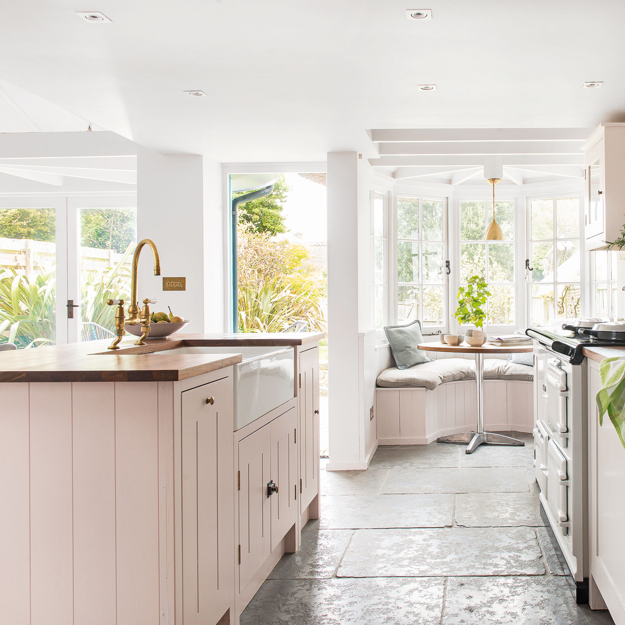 Cocina con gabinetes con paneles rosas y pisos de piedra